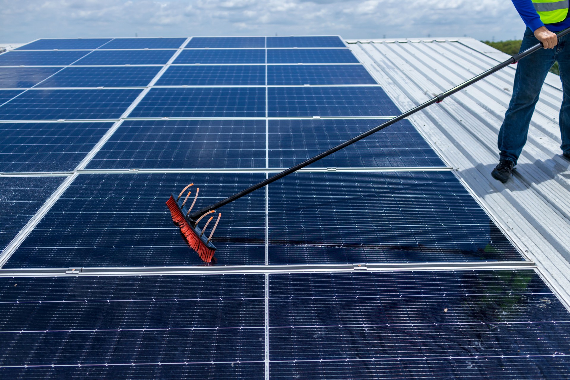 Worker Cleaning solar panels with brush and water. Worker cleaning solar modules in a Solar Energy Power Plant